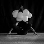 Artistic dance performance with balloons in a grayscale setting.