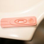 A detailed close-up of a pink pregnancy test kit on a white surface.